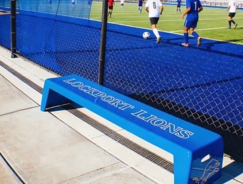 Blue Easy Stack Bench with Lockport Lions graphics beside an athletic field