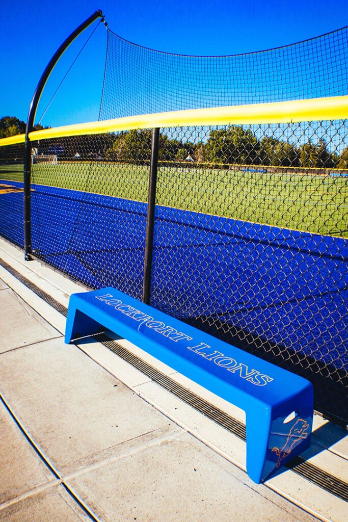 Blue Easy Stack Bench beside a fence at an athletic field