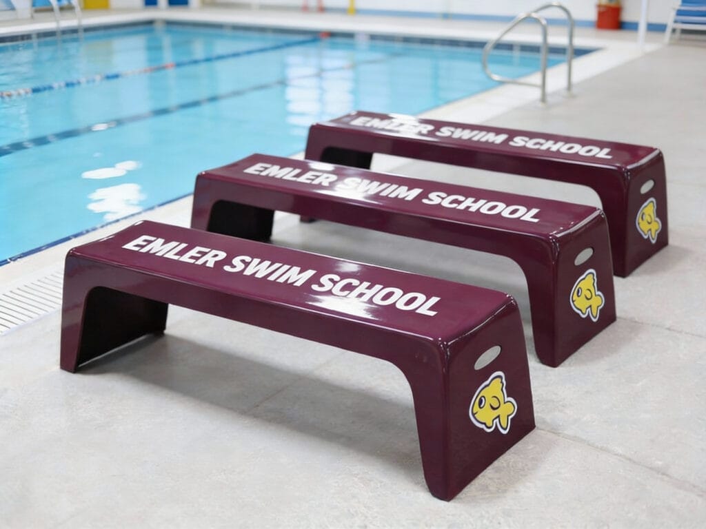 Maroon Easy Stack Benches with Emler Swim School graphics on a pool deck