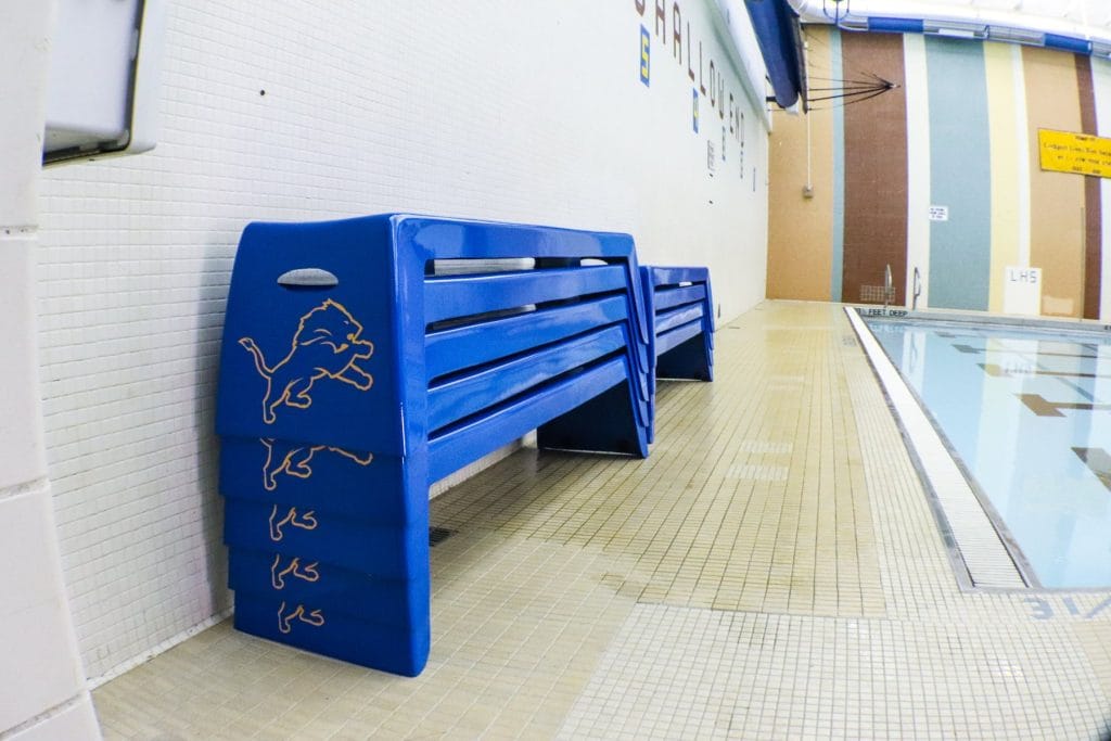 Stacked blue Easy Stack Benches with Lockport Lions logo by an indoor pool